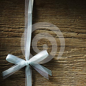 Decorative white ribbon and bow over wooden background