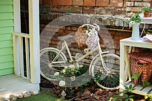 Decorative white vintage bicycle against brick wall. Old bicycle parked against a stone wall in garden. Street decoration backyard