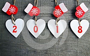 Decorative white wooden Christmas hearts and red mittens with 2018 numbers on wooden background with copy space.Happy New Year 201