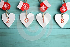 Decorative white wooden Christmas hearts and red mittens with 2018 numbers on blue wooden background with copy space.Happy New Yea