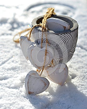 decorative white wooden hearts in the snow held by strings in a pot put on the snow