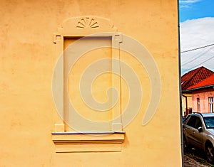 Decorative window on an old yellow plaster wall