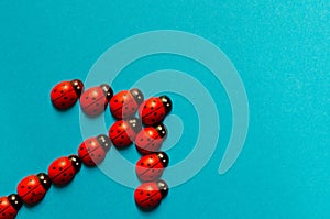 Decorative wooden ladybugs on blue background with copy space. Ladybug arrow. Ladybug pattern