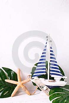 Decorative wooden toy boat, sea star and tropical plant leaves