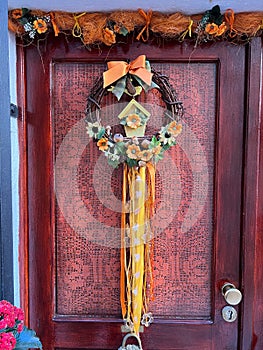 Decorative wreath with flowers and a bird hangs on the front door