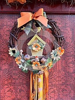 Decorative wreath with flowers on the front door. Close-up