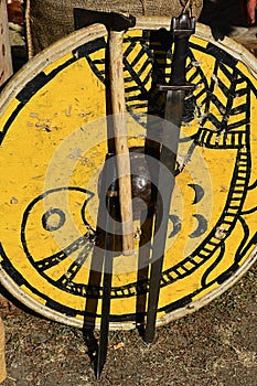 Decorative yellow medieval round shield with bird painting, one handed sword, light battle axe and machette