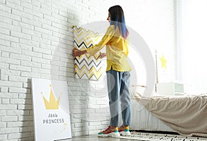 Decorator hanging picture on brick wall. Children`s room interior design