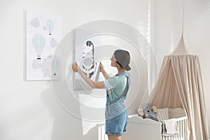 Decorator hanging picture on wall. Children`s room interior design