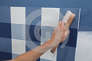 Decorator hanging wallpaper with work tool in motion
