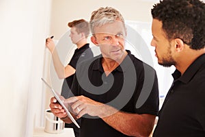 Decorator instructing colleague painting a room photo