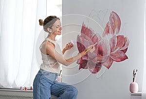 Decorator painting flower on white wall. Interior design