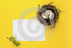 Decorted Easter eggs in a bird`s nest on a yellow background