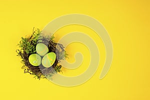 Decorted Easter eggs in a bird`s nest on a yellow background