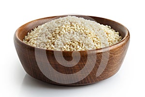 Decorticated sesame seeds in dark wooden bowl.