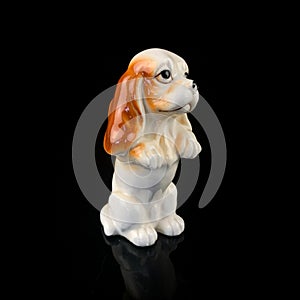 Antique figurine of a dog on a black isolated background. puppy toy.