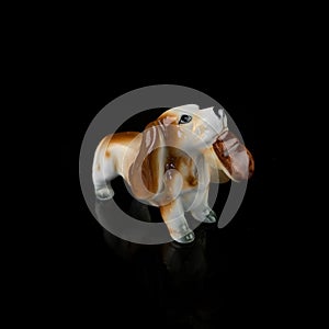 Antique figurine of a dog on a black isolated background. puppy toy.