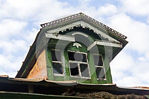 Decrepit dormer-window on the roof of a wooden Russian hut