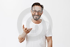 Dedicate everything to you. Charming grateful european male with beard and stylish haircut in glasses, pointing with