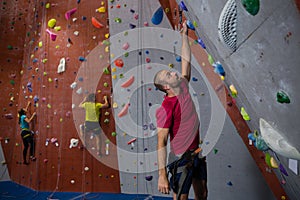 Dedicated athletes and trainer climbing wall in club