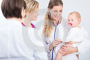 Dedicated female physician holding a cute baby girl in her arms