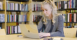 Dedicated female student working on laptop in the library