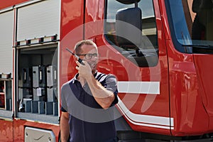 A dedicated firefighter, captured in a moment of communication, stands before a modern firetruck, showcasing the