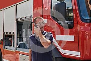 A dedicated firefighter, captured in a moment of communication, stands before a modern firetruck, showcasing the