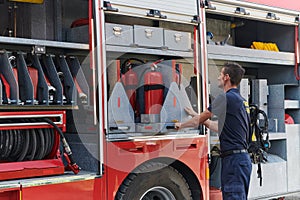A dedicated firefighter preparing a modern firetruck for deployment to hazardous fire-stricken areas, demonstrating