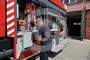 A dedicated firefighter preparing a modern firetruck for deployment to hazardous fire-stricken areas, demonstrating