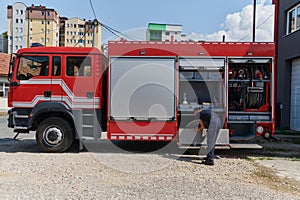 A dedicated firefighter preparing a modern firetruck for deployment to hazardous fire-stricken areas, demonstrating