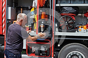 A dedicated firefighter preparing a modern firetruck for deployment to hazardous fire-stricken areas, demonstrating