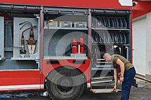 A dedicated firefighter preparing a modern firetruck for deployment to hazardous fire-stricken areas, demonstrating