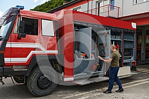 A dedicated firefighter preparing a modern firetruck for deployment to hazardous fire-stricken areas, demonstrating