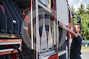 A dedicated firefighter preparing a modern firetruck for deployment to hazardous fire-stricken areas, demonstrating