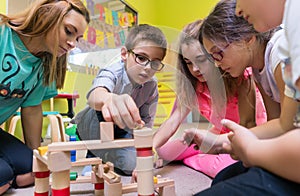 Dedicated kindergarten teacher helping children with the construction of a train