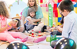 Dedicated kindergarten teacher holding a shy girl while watching photo