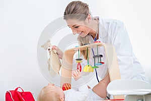 Dedicated pediatrician playing with a healthy and active baby photo