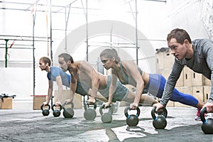 Dedicated people doing pushups with kettlebells at crossfit gym