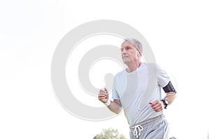 Dedicated senior man jogging against sky