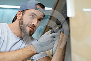 Dedicated to excellence. Close up portrait of young repairman, professional plumber looking cheerful while fixing a sink