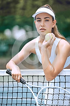 Dedicated young female tennis player holding a tennis racket and ball while leaning over a net. Hispanic woman ready for