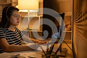 Dedicated Young Woman Studying Online Late at Night in Her Home Office