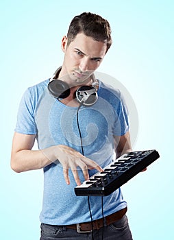 Deejay with headphones pressing keys on midi keyboard