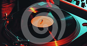 Deejay spinning vinyl musical record on turntable during dj rave, close-up. Nightlife and music