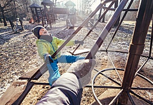 Deep autumn on child playground. Boy turns on the carousel