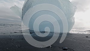 Deep blue iceberg over the black sand in slow-mo