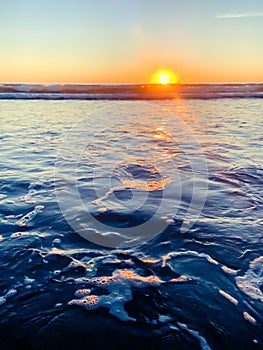 deep blue ocean water and sea foam at sunset