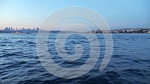 Deep blue sea waves against city in dusk view from ship