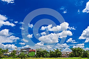 Deep blue sky with bright white clouds with fileds and houses